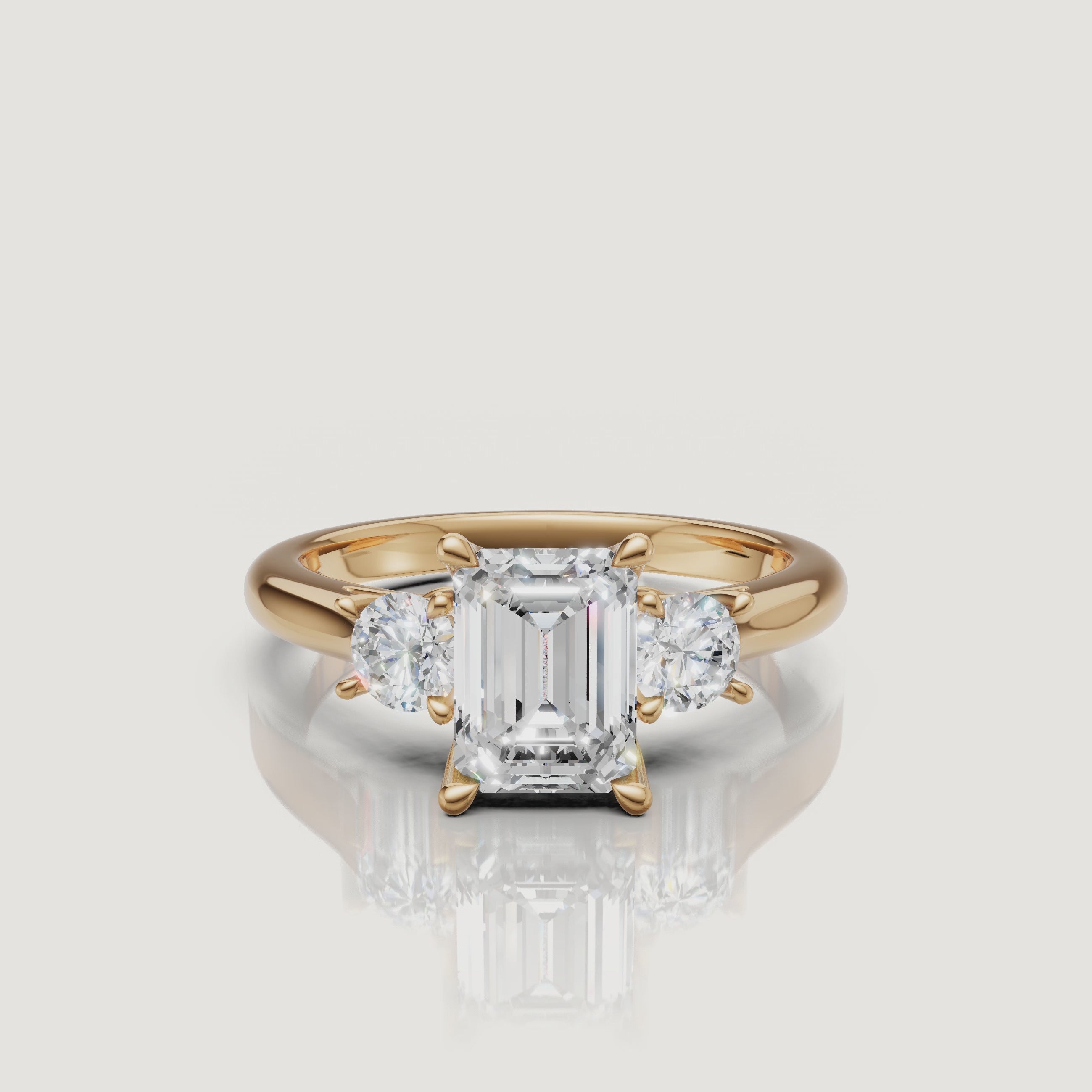 360-degree video showcase of the Raul Diamonds emerald cut three-stone ring in yellow gold, highlighting the hall-of-mirrors effect and the sparkle of the round side diamonds.