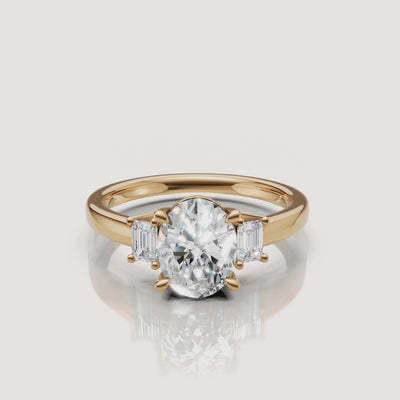 360-degree video showcase of a Raul Diamonds yellow gold engagement ring featuring a brilliant oval-cut center diamond and emerald-cut side stones, sparkling under studio lighting