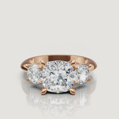 Cinematic close-up of the Sophia rose gold cushion trilogy ring, focusing on the warm blush metal and the brilliant light return of the cushion-shaped center stone.