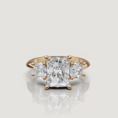 360-degree video showcase of the Raul Diamonds radiant cut three-stone ring in yellow gold, highlighting the "crushed ice" brilliance of the center stone and round side diamonds.