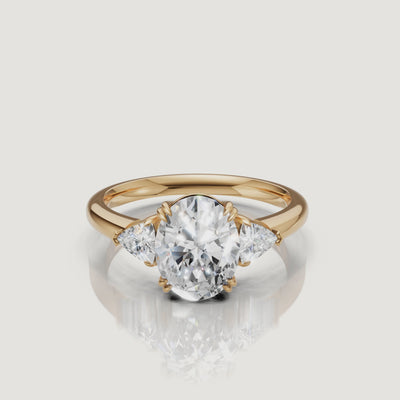 video of oval cut lab grown diamond engagement ring with trillion side stones in 14k yellow gold