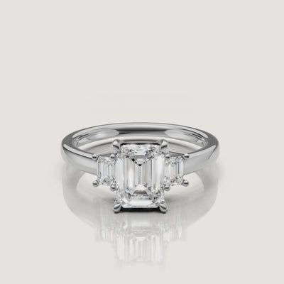 High-definition video of a Rual Diamonds white gold double emerald cut engagement ring, highlighting the distinct 'hall of mirrors' light effect of the parallel diamonds and the shimmering pavé bridge bridge