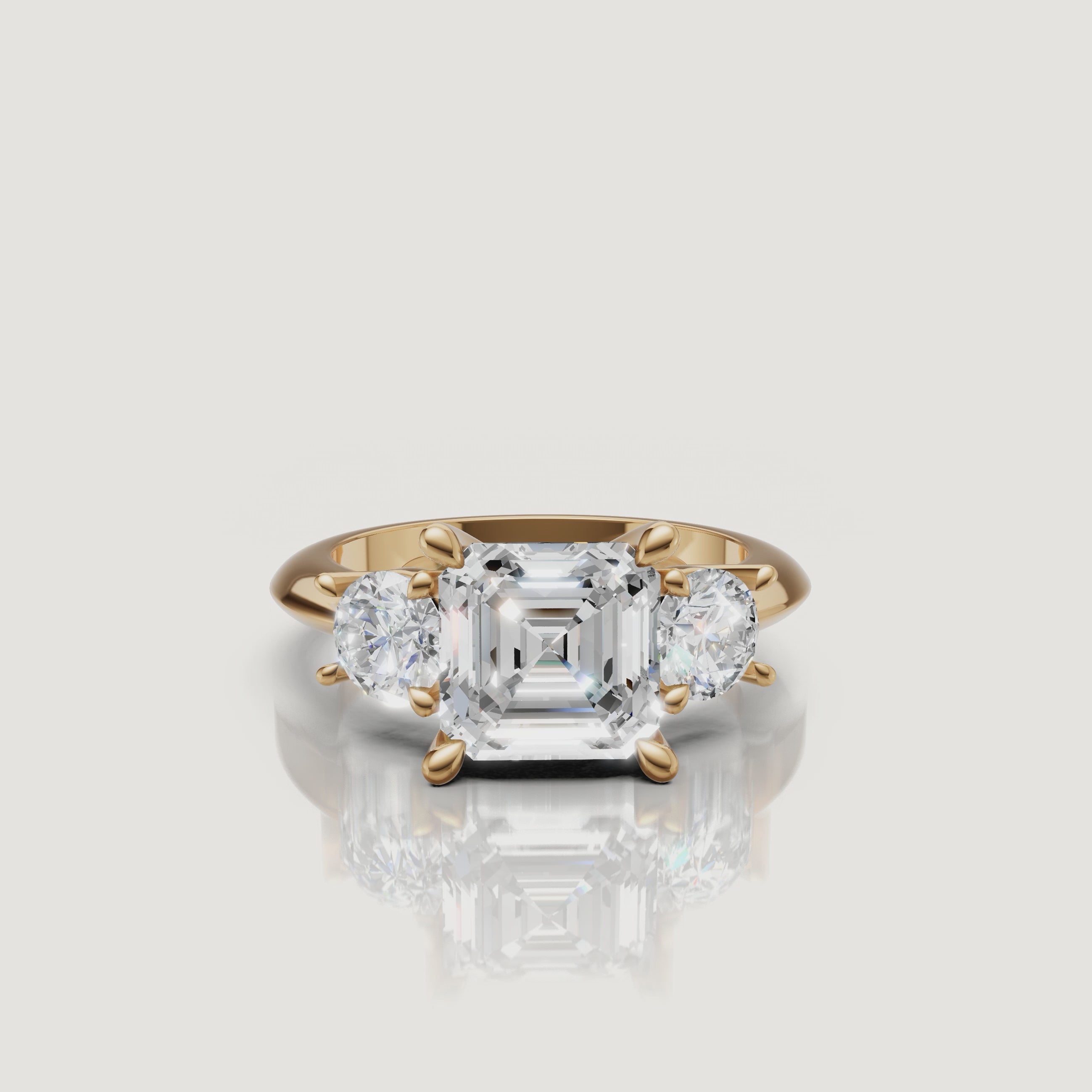 360-degree video showcase of the Raul Diamonds Asscher cut three-stone ring in yellow gold, highlighting the hall-of-mirrors effect and the sleek baguette side stones.