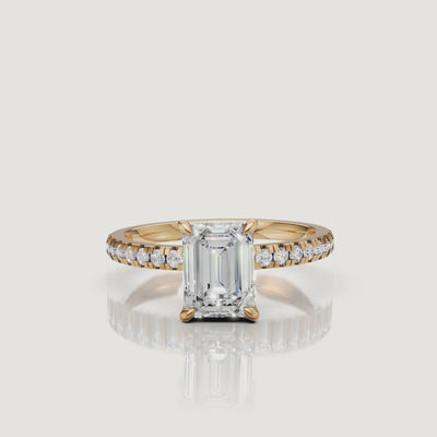 High-definition 360-degree video of a Raul Diamonds emerald cut engagement ring in 18k yellow gold, featuring a shimmering pavé-set diamond band and a 4-prong claw setting
