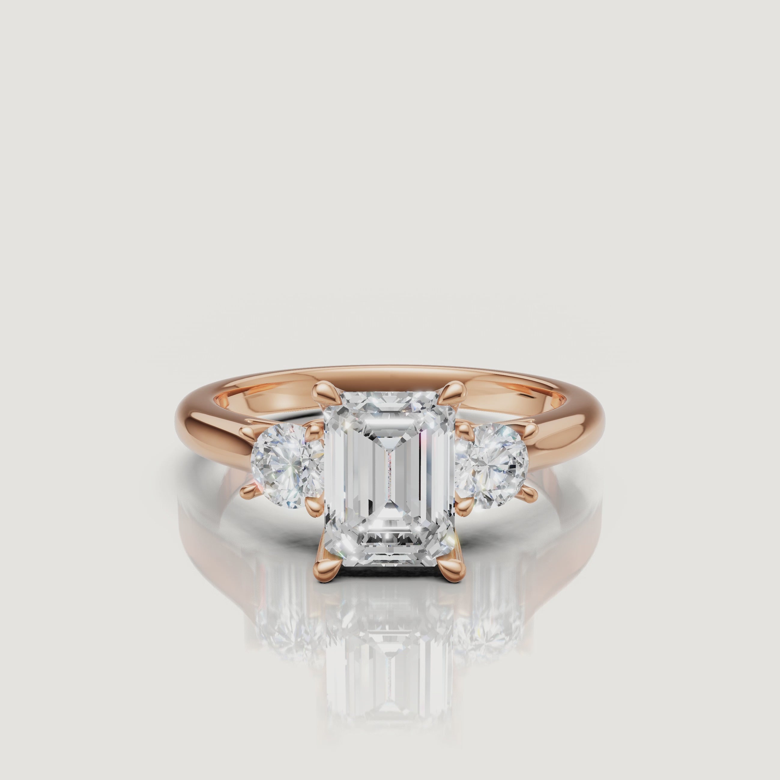 Cinematic close-up of the Elena rose gold emerald cut trilogy ring, focusing on the warm blush metal and the clear, step-cut facets of the center diamond.