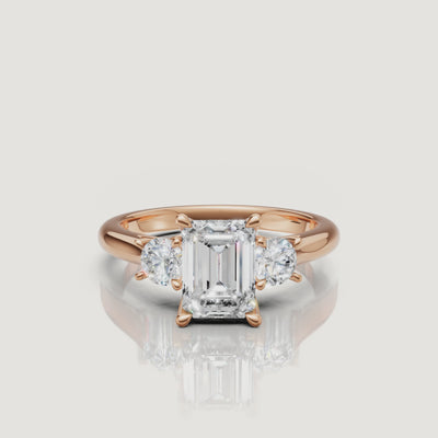 Cinematic close-up of the Elena rose gold emerald cut trilogy ring, focusing on the warm blush metal and the clear, step-cut facets of the center diamond.