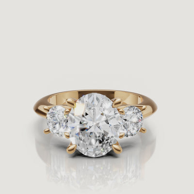 360-degree video showcase of the Raul Diamonds oval cut three-stone ring in yellow gold, highlighting the brilliant fire of the oval center and round side diamonds.
