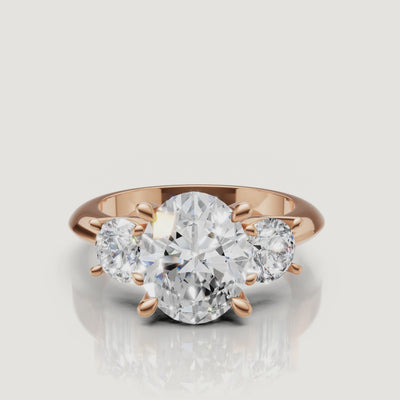 Cinematic close-up of the Seraphina rose gold oval trilogy ring, focusing on the warm blush metal and the exceptional light performance of the oval-shaped center stone.