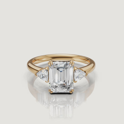 video of emerald cut lab grown diamond engagement ring with trillion side stones in 14k yellow gold