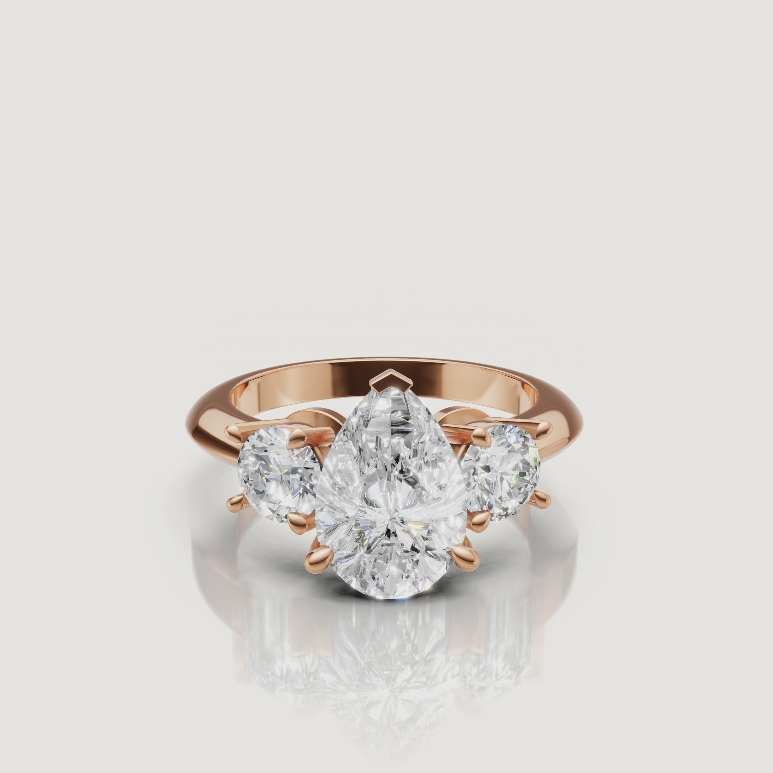 Cinematic close-up of the Aurora rose gold pear trilogy ring, focusing on the warm blush metal and the superior light performance of the pear-shaped center stone.
