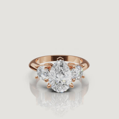 Cinematic close-up of the Aurora rose gold pear trilogy ring, focusing on the warm blush metal and the superior light performance of the pear-shaped center stone.