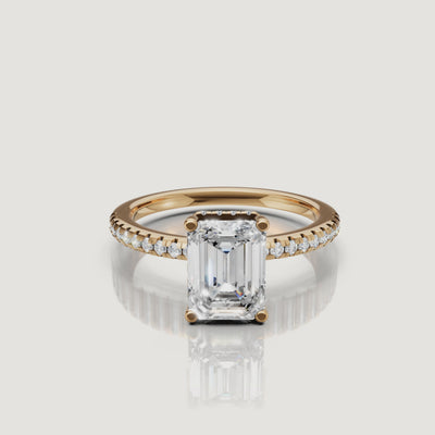 A detailed 4K video of a yellow gold emerald cut diamond ring by Raul Diamonds, rotating to show the hidden halo and brilliant pavé-set diamonds.