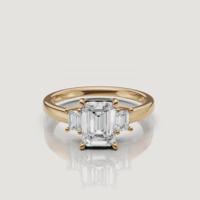 A high-definition 360-degree rotation of a Rual Diamonds double emerald cut linear two-stone ring in 14k yellow gold, showcasing the unique diamond-encrusted pavé bridge bridge and step-cut brilliance