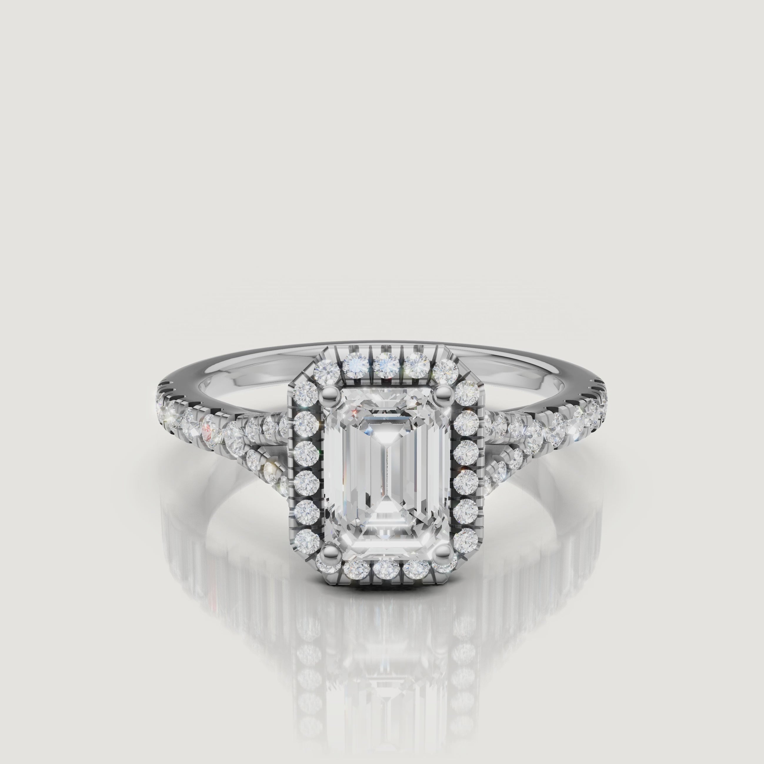 High-definition video of a white gold emerald cut diamond halo ring, demonstrating the hall-of-mirrors effect of the center stone and the brilliance of the side diamonds