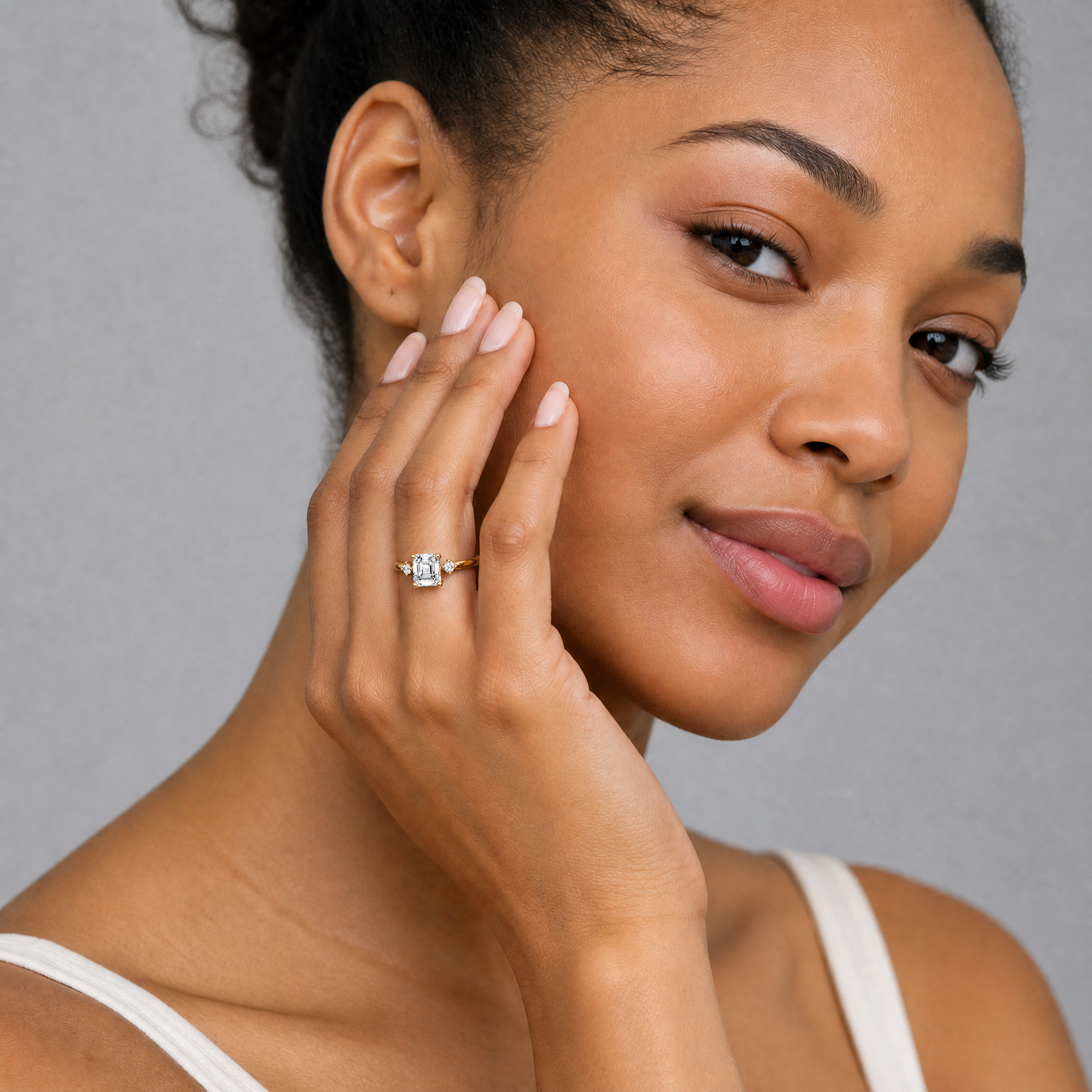 Woman wearing Raul Diamonds asscher cut lab grown diamond engagement ring in 14K rose gold with elegant side stones