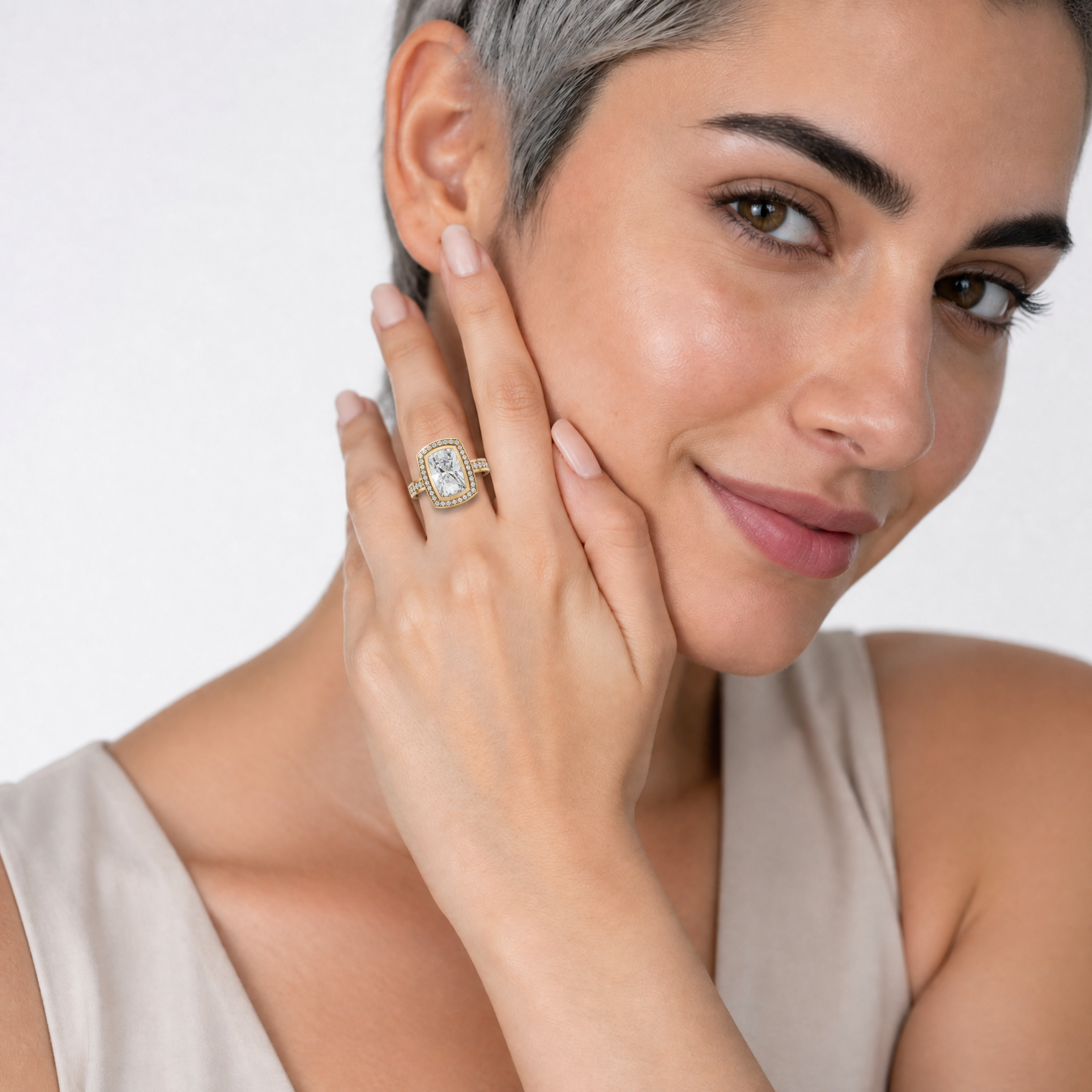 Woman wearing Raul Diamonds cushion cut halo engagement ring with pavé diamond band in gold.