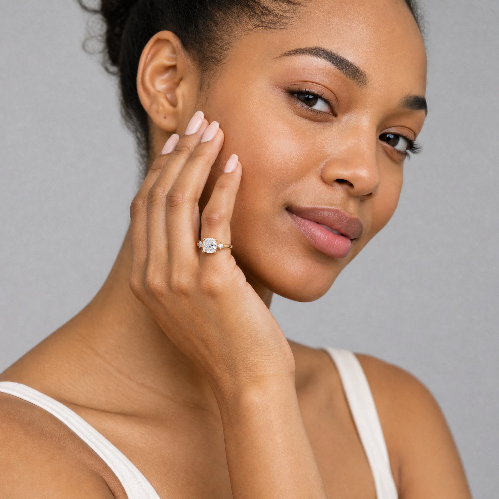 Model wearing Raul Diamonds cushion cut lab grown diamond engagement ring in 14K yellow gold with round side stones