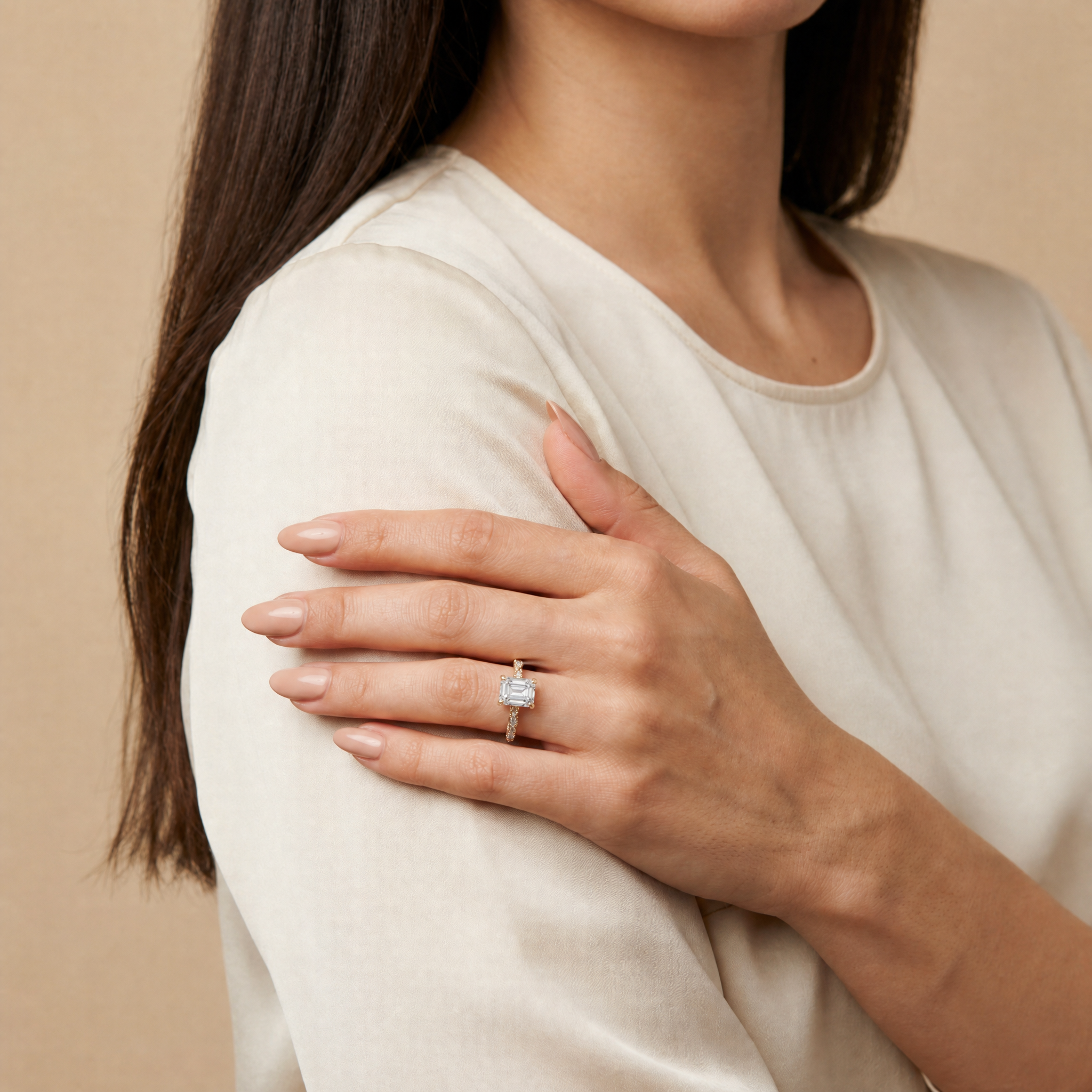 Model wearing Raul Diamonds emerald cut lab grown diamond engagement ring in 14K gold with elegant twisted pavé band