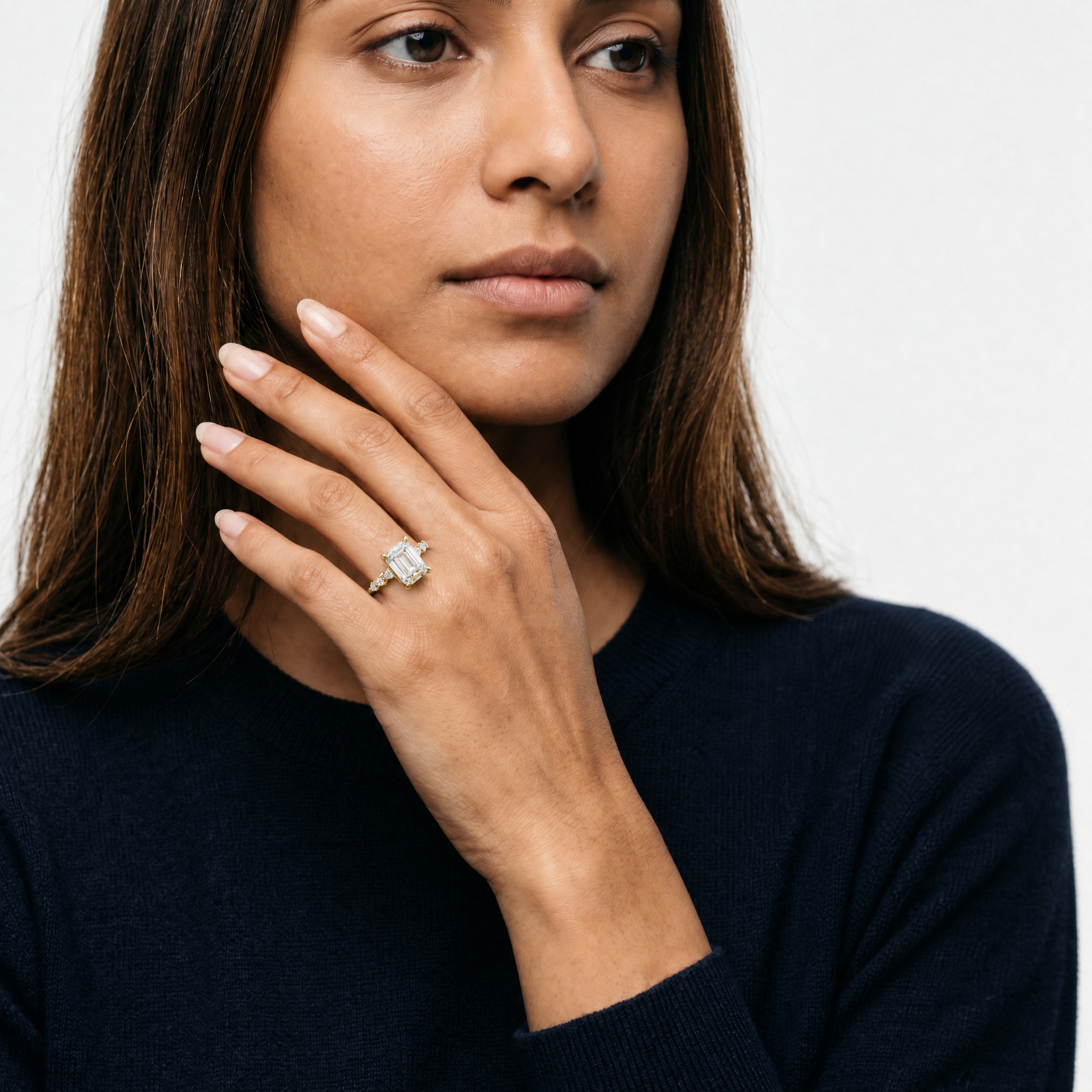 Model wearing emerald cut lab grown diamond engagement ring in 14K gold with marquise side stones by Raul Diamonds