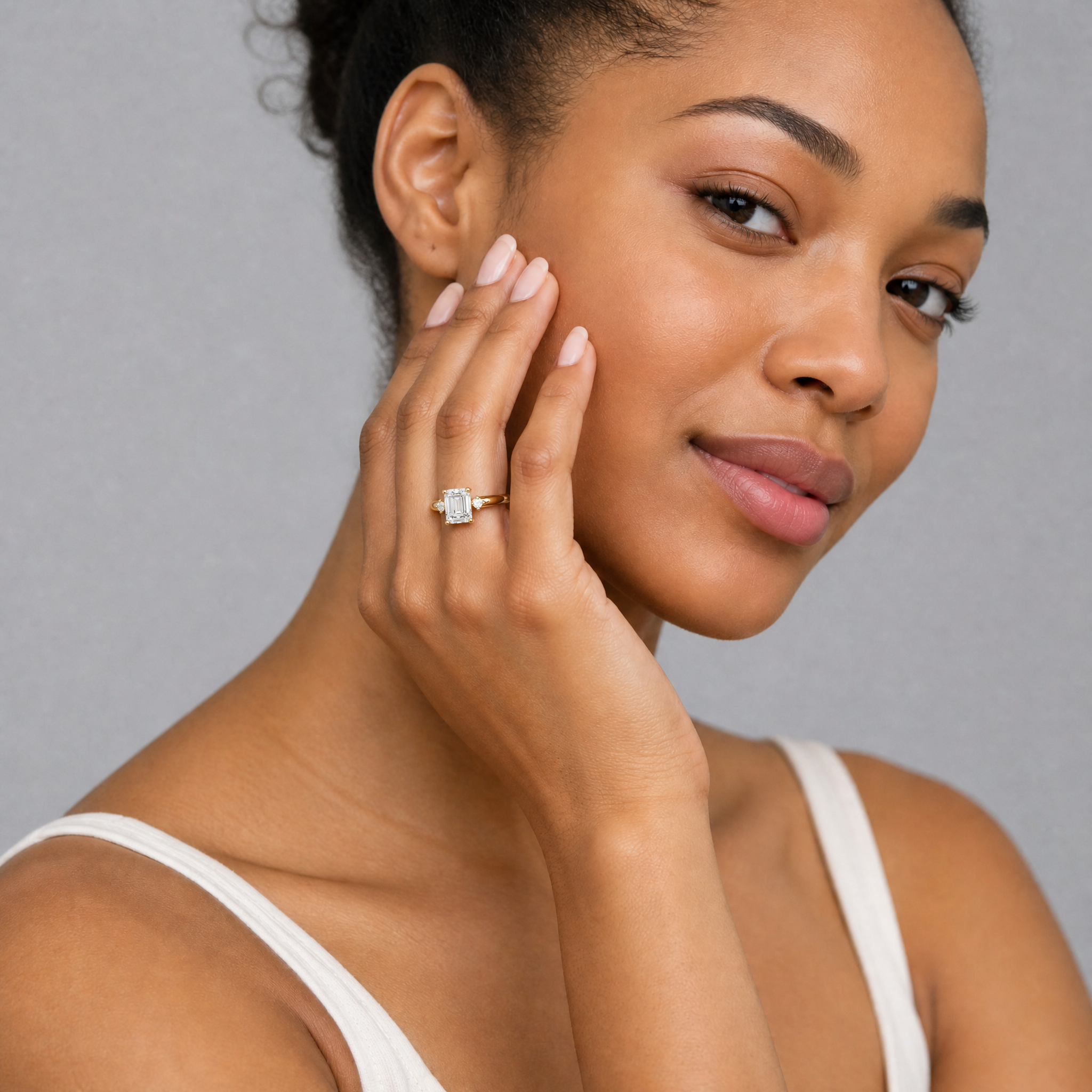 Model wearing Raul Diamonds emerald cut lab grown diamond engagement ring in 14K yellow gold with round side stones