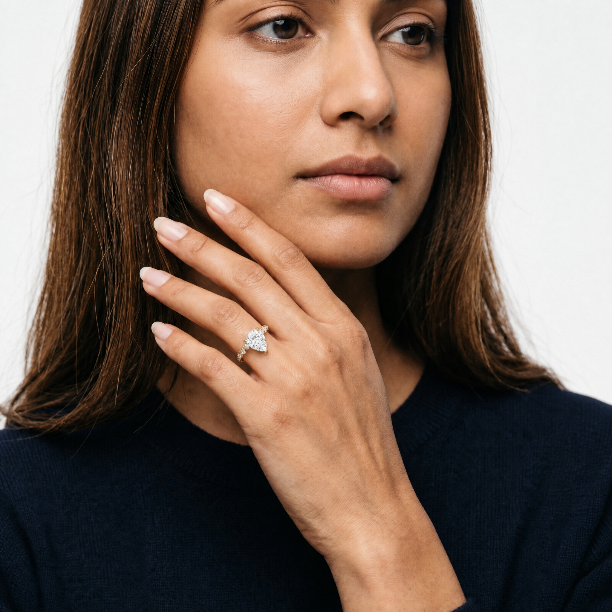 Model wearing pear cut lab grown diamond engagement ring in 14K gold with marquise side stones by Raul Diamonds