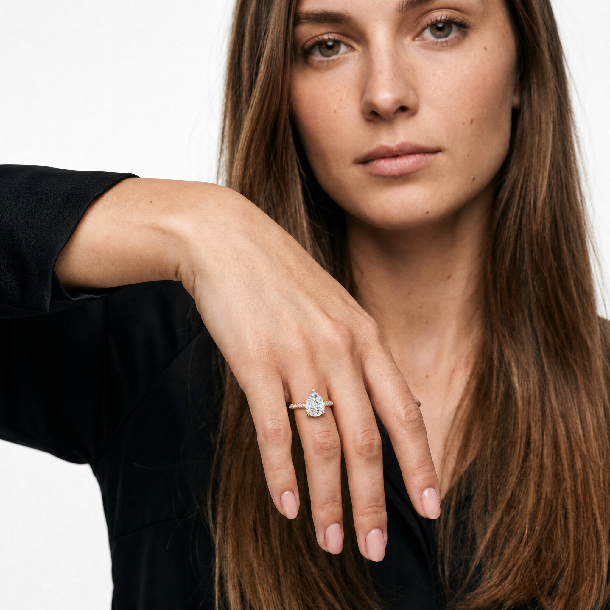 Model wearing a pear cut lab grown diamond engagement ring with pavé band in 14K gold by Raul Diamonds