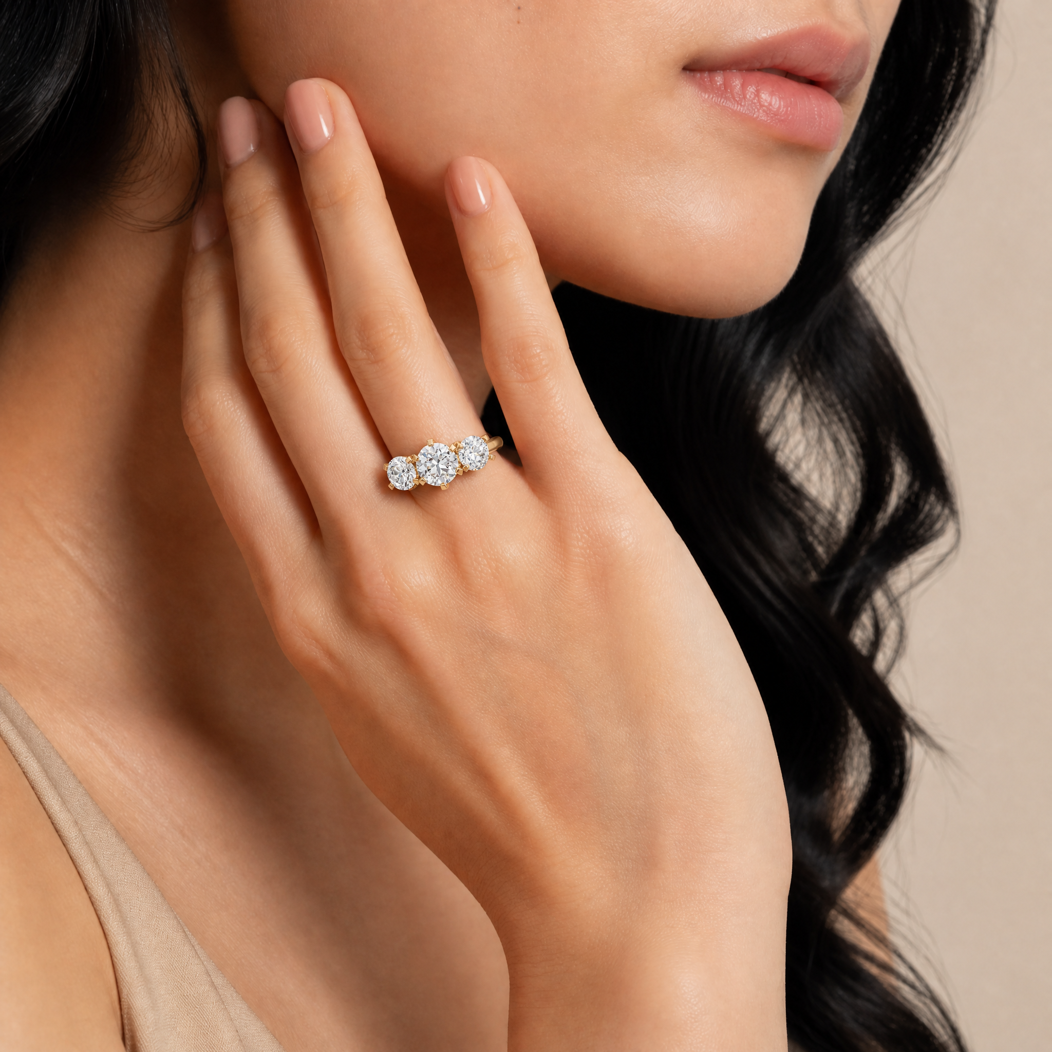Model wearing Raul Diamonds round three stone diamond engagement ring in yellow gold with classic trilogy setting