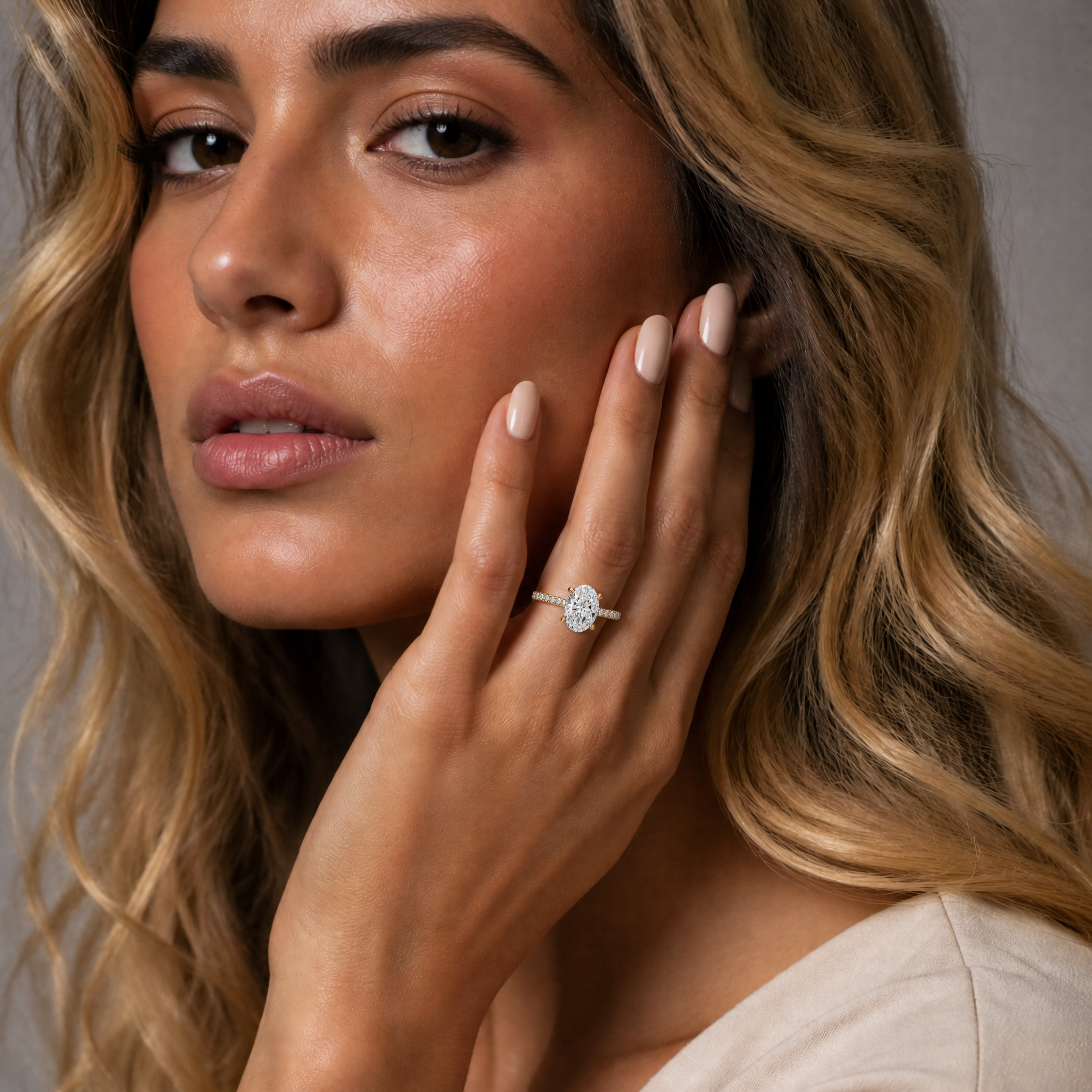 Model wearing Raul Diamonds oval cut lab grown diamond engagement ring in 14K yellow gold with pavé band and classic solitaire setting