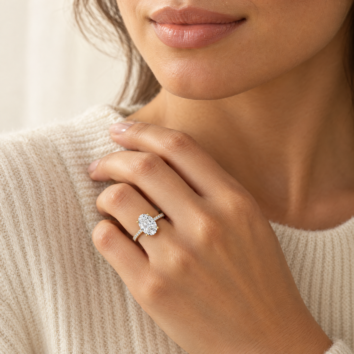 Oval lab-grown diamond engagement ring with pavé band worn on the hand