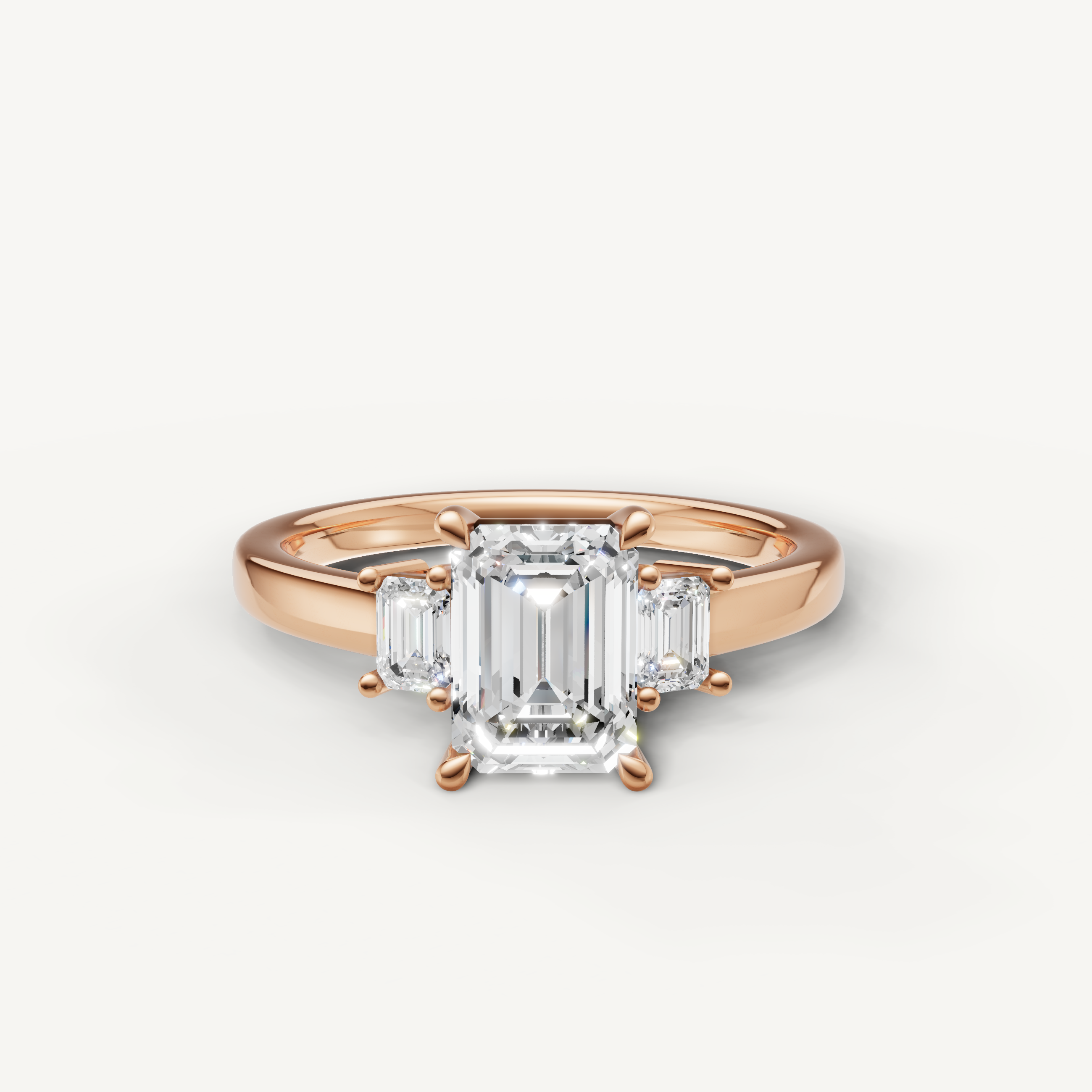 Emerald cut lab grown diamond three stone engagement ring in 14K rose gold with step cut side stones