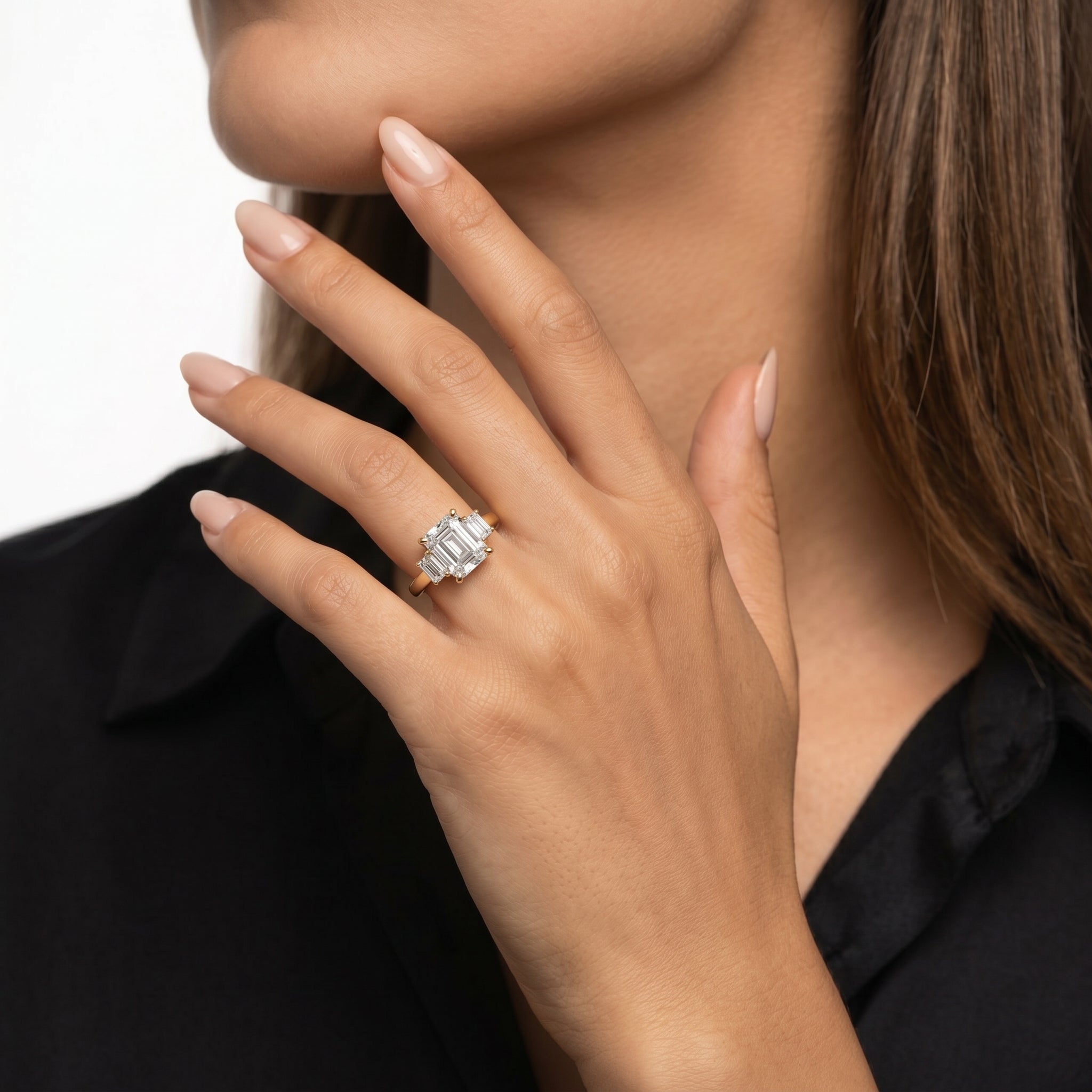 Close-up of a hand model wearing a Rual Diamonds double emerald cut two-stone diamond engagement ring, featuring a linear orientation and a unique pavé diamond bridge bridge detail